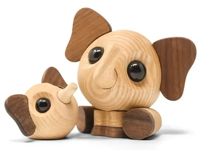 To elefantfigurer af træ med store runde sorte øjne og overdimensionerede ører, den ene sidder oprejst og den anden ligger på siden.