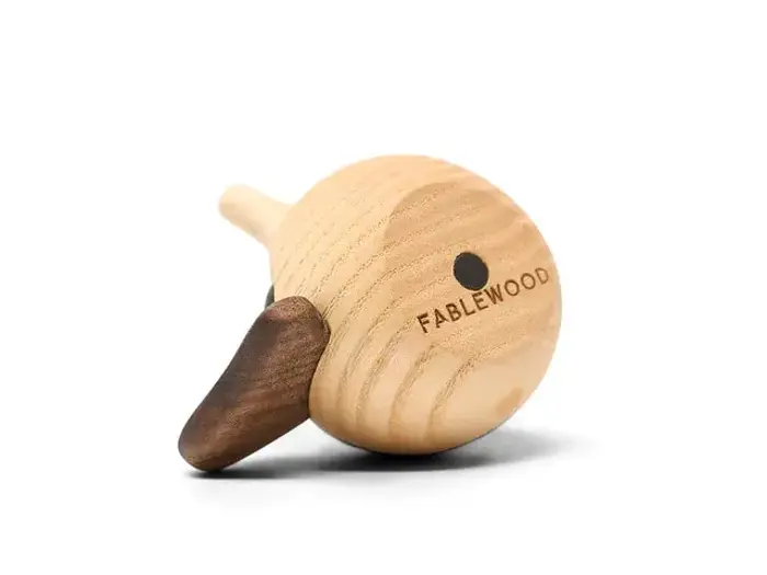 Et trælegetøj formet som en fugl med en rund krop, et lille næb og en vinge. Mærkenavnet FABLEWOOD er indgraveret på siden.