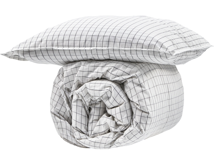 En hvid pude og en sammenrullet dyne med et sort gittermønster på en almindelig hvid baggrund.