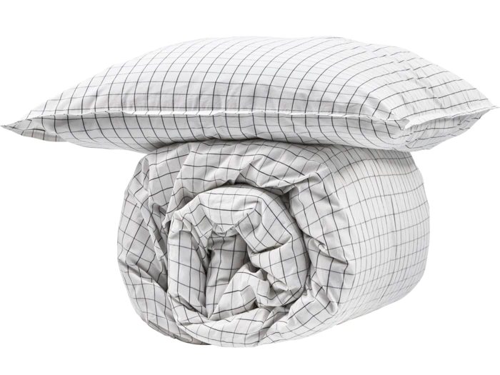 En hvid pude og en sammenrullet dyne med et sort gittermønster på en almindelig hvid baggrund.