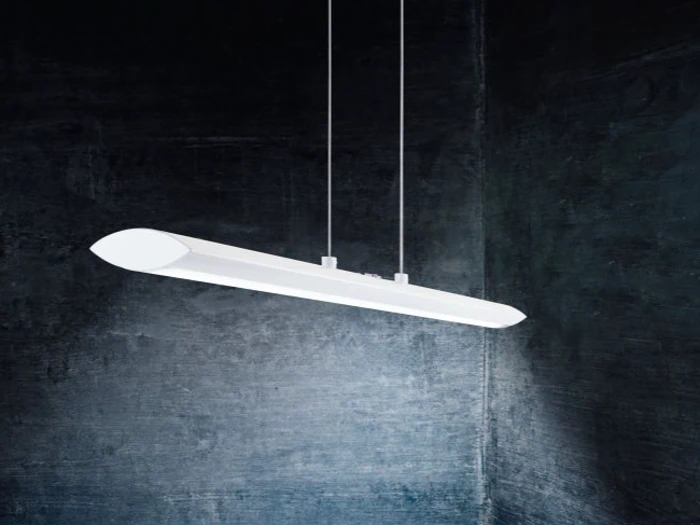 En moderne hvid pendel hænger fra loftet i to kabler mod en mørk, struktureret væg.