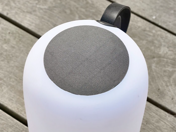 Et hvidt cylindrisk objekt med en sort cirkulær top og et sort håndtag, placeret på en træoverflade.