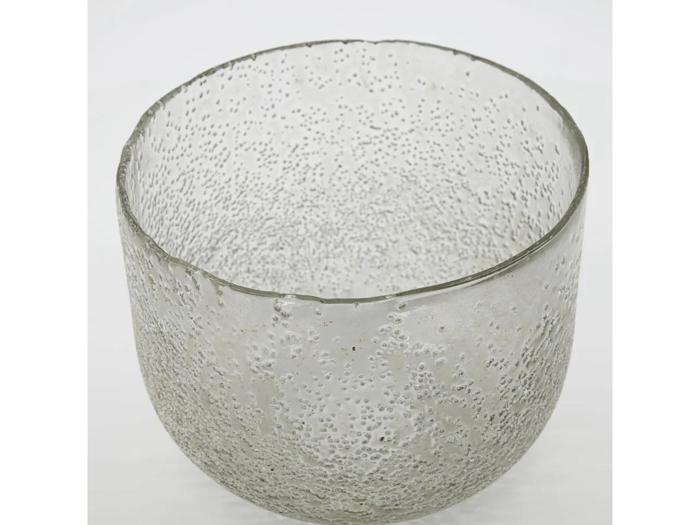 En gennemsigtig glasskål med en struktureret, boblende overflade mod en almindelig hvid baggrund.