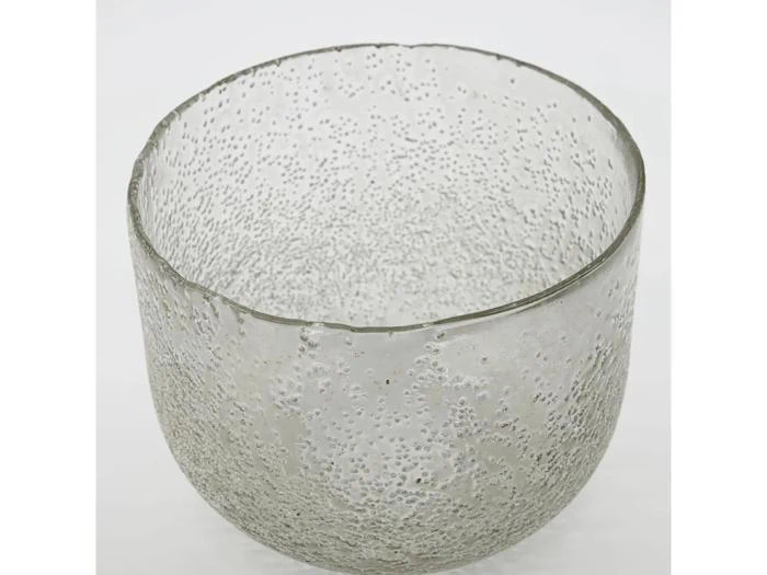 En gennemsigtig glasskål med en struktureret, boblende overflade mod en almindelig hvid baggrund.