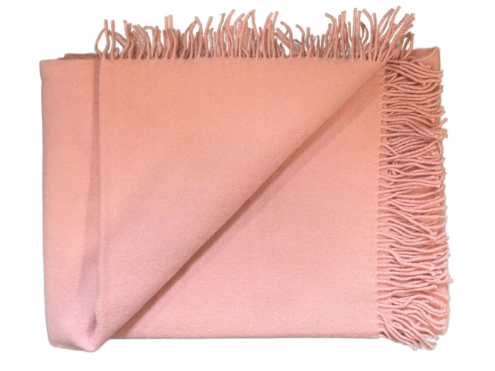 Et foldet, lyserødt tæppe med frynser på to kanter, vist på en hvid baggrund.