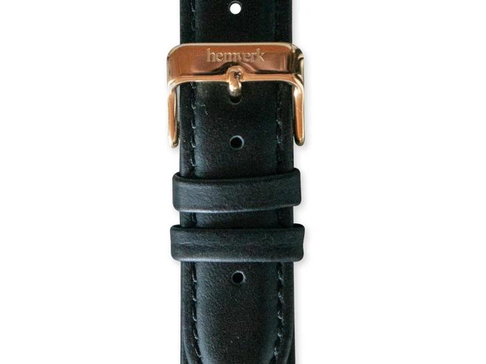 Nærbillede af en sort læderurrem med et guldspænde med ordet hemverk indgraveret. Remmen har to løkker og synlige syninger langs kanterne.