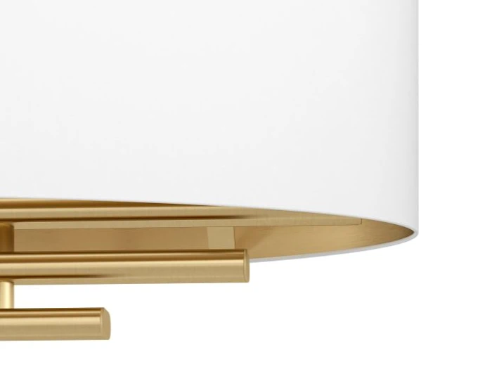 Nærbillede af en moderne lampe med hvid, cylindrisk skærm og guldfarvet metalfod med rene, geometriske linjer.