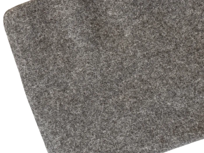 Et nærbillede af et rektangulært stykke gråt filtstof mod en hvid baggrund.