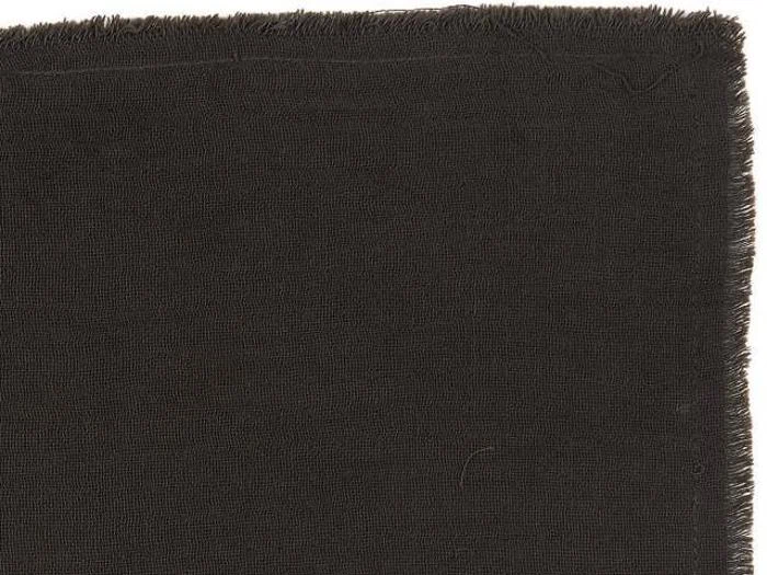 Et nærbillede af et stykke mørkebrunt stof med synlig struktur og flossede kanter på toppen og i højre side.
