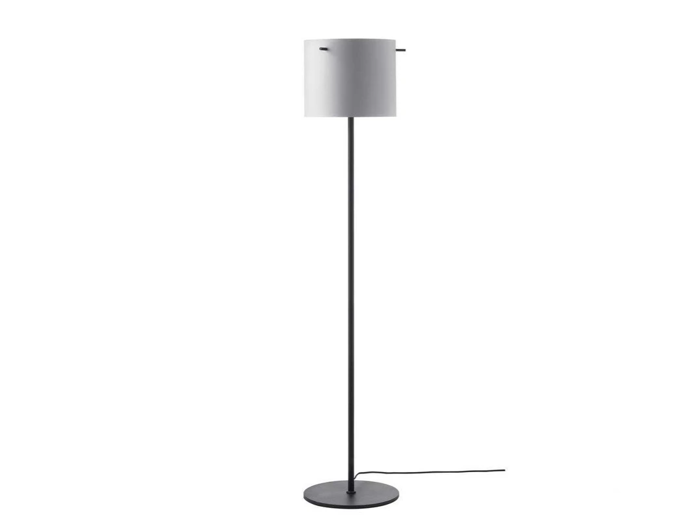 En moderne gulvlampe med et slankt sort stativ, en rund fod og en cylindrisk hvid lampeskærm; der går en strømledning ud fra foden.
