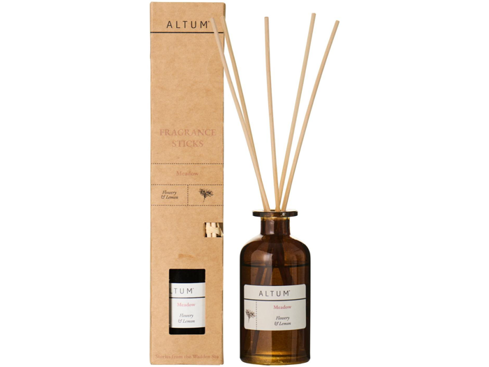 En brun glasflaske med etiketten ALTUM Meadow med sivdiffusorpinde ved siden af den høje papemballage, begge med Honey & Lemon-duft.