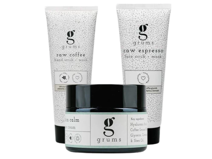 Tre Grums-hudplejeprodukter: en raw coffee hand scrub, en raw espresso face scrub og en calm cream i en krukke, alle med minimalistisk hvid og sort indpakning.