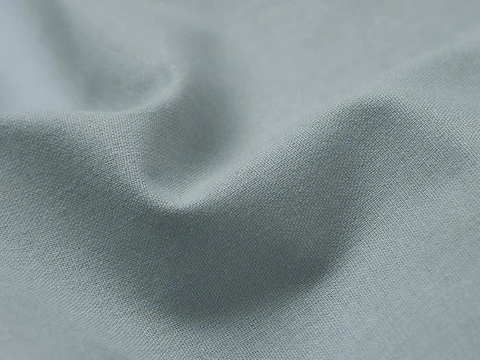 Nærbillede af lyseblåt stof med synlig vævestruktur og blide, bløde folder, der skaber subtile skygger.