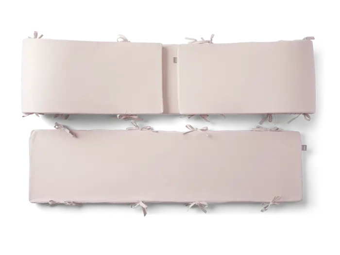 To rektangulære, lyserøde sengerande med stofbånd langs kanterne, vist på en almindelig baggrund.