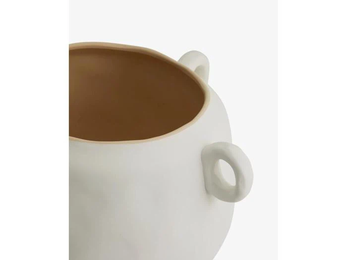 Et nærbillede af en hvid keramikpotte med brunligt indre og afrundede, snoede håndtag mod en ensfarvet baggrund.