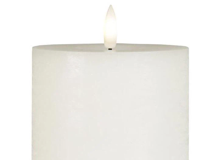 Et stort hvidt bloklys med en tændt flamme i toppen, vist mod en almindelig hvid baggrund.