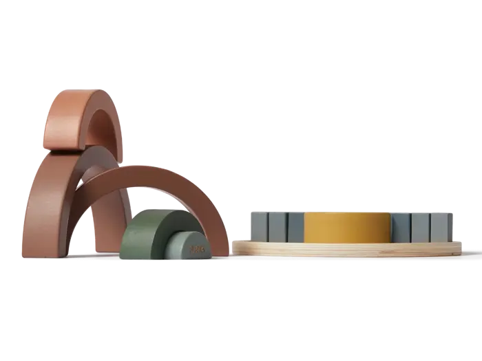 Stablelegetøj af træ i jordfarver er arrangeret i buer til venstre og stablet i cirkulære lag til højre mod en almindelig baggrund.