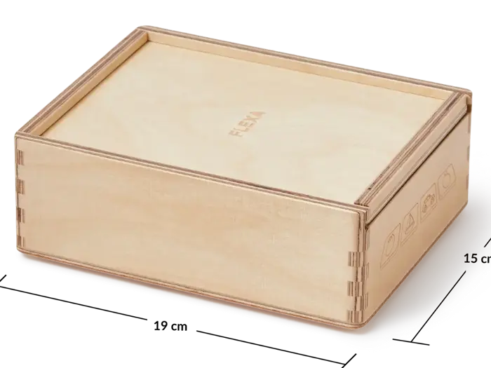 En rektangulær lys trækasse med monteret låg, enkelt snedkerarbejde og diskrete symboler på den ene side. Kassen er mærket FLEXA på låget.