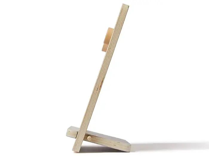 Et sidebillede af en billedramme i træ, der står på et stativ, og som viser den tynde profil og de lagdelte trækanter.