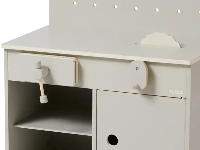 Nærbillede af et lyst legekøkken til børn med komfur, ovn og hylder med enkle træknopper og -håndtag.