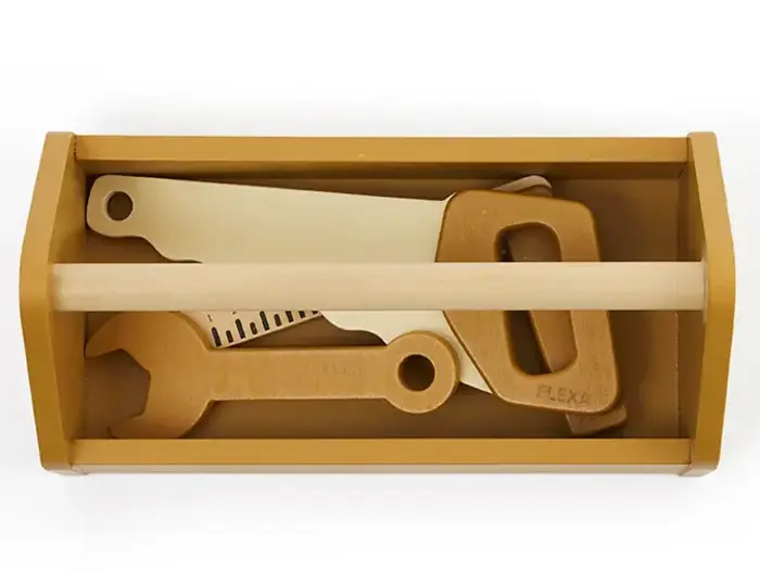 En legetøjsværktøjskasse af træ, der indeholder en legetøjsnøgle, en sav og en lineal, alt sammen lavet af lyst og mørkebrunt træ.