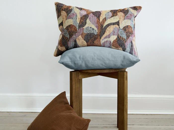 Tre puder arrangeret på og omkring en træskammel med en almindelig lys væg og trægulv i baggrunden.