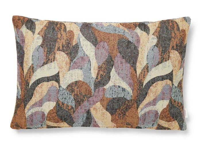 Rektangulær pude med et abstrakt mønster i jordfarver som brun, beige, sort og dæmpet lilla på en hvid baggrund.