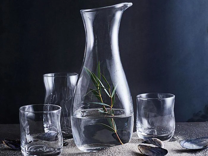 En glaskande med en plante i.