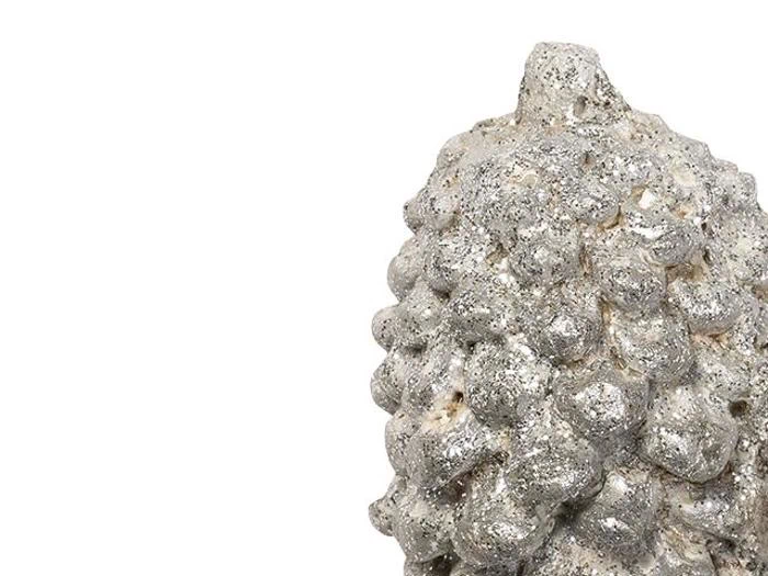 Nærbillede af en sølvfarvet, ujævn, kogleformet dekoration mod en hvid baggrund.