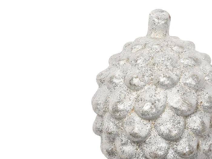 Et struktureret, sølvfarvet, kogleagtigt ornament med en kort stilk, placeret i højre side mod en hvid baggrund.