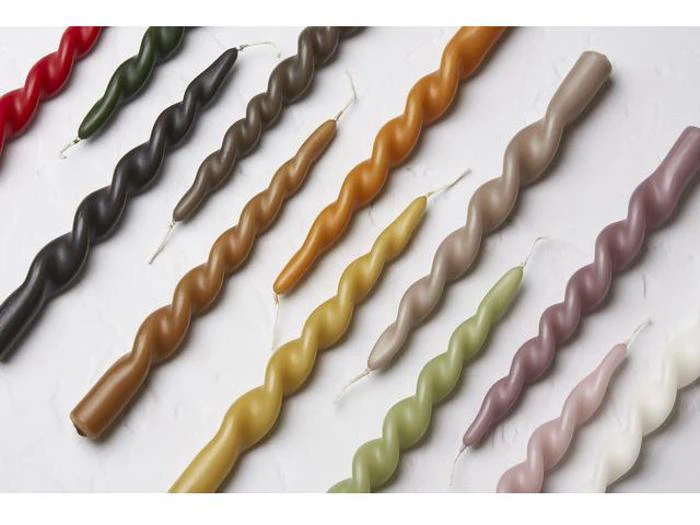 Assorterede snoede keglelys i forskellige farver, arrangeret diagonalt på en hvid struktureret overflade.