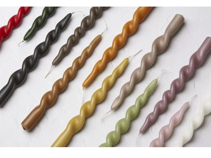 En række farverige, snoede keglelys er arrangeret diagonalt på en hvid overflade.