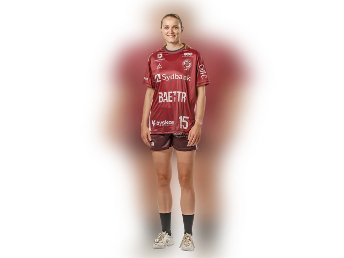 En kvinde i en rødbrun sportsdragt med påskriften »SydBank« og nummeret 15 står og smiler foran en hvid baggrund.