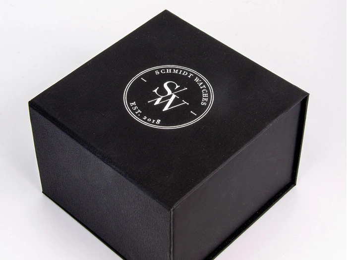 En sort firkantet æske med logoet Schmidt Watches SW Est. 2018 i hvidt på låget, fotograferet mod en almindelig hvid baggrund.