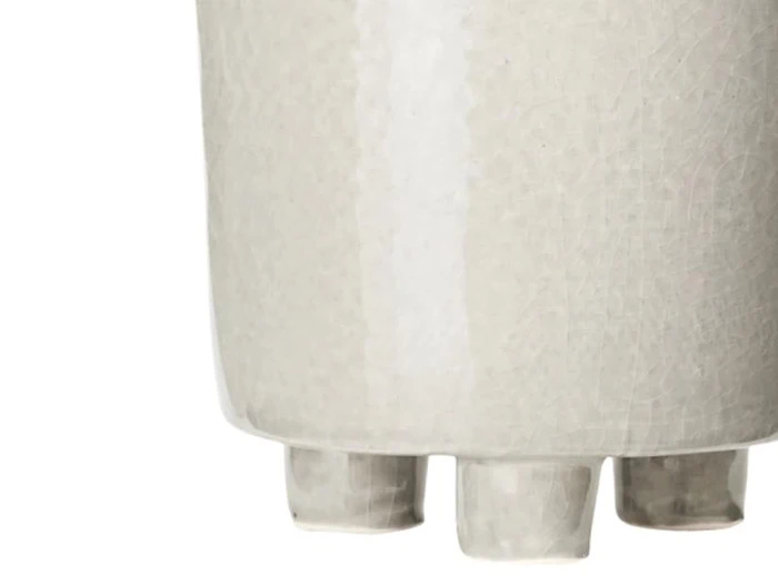 Nærbillede af bunden af en lys keramikvase med tre korte, afrundede fødder.