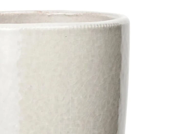 Nærbillede af den øverste kant af en lysegrå keramisk kop eller krus med en glat, let struktureret overflade mod en hvid baggrund.