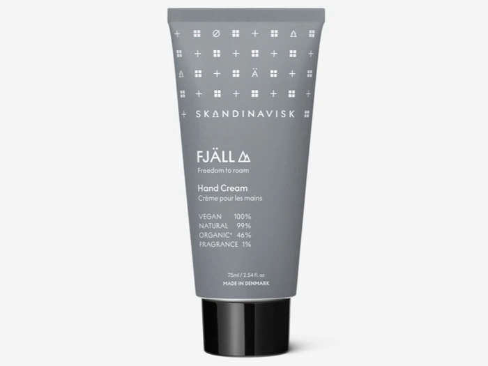 En grå tube med Skandinavisk FJÄLL håndcreme, der er mærket som vegansk, naturlig, økologisk og med 1 % parfume, står oprejst på en hvid baggrund.