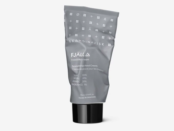En grå tube med SKANDINAVISK FJÄLL Scandinavian Hand Cream med hvid tekst, mærket som vegansk, økologisk og fremstillet i Danmark. Tuben ser lidt krøllet ud.