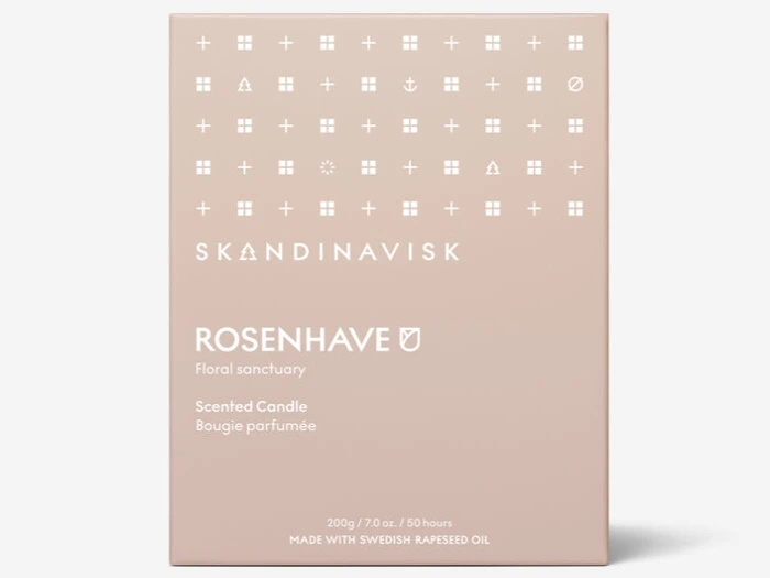 En beige æske med mærket SKANDINAVISK ROSENHAVE duftlys, med hvide minimalistiske symboler og en tekst, der beskriver det som et blomsterhelligdom lavet med svensk rapsolie.