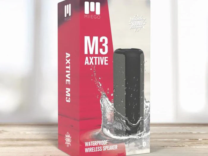 En æske til den vandtætte trådløse højttaler MIEGO M3 AXTiVE med et billede af højttaleren med vandsprøjt omkring sig og fede røde og hvide etiketter.