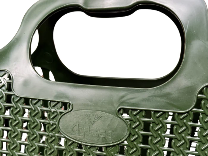 Nærbillede af et grønt plastkurvehåndtag med vævet mønster og et ovalt etiketområde med indrykket tekst og et lille logo.