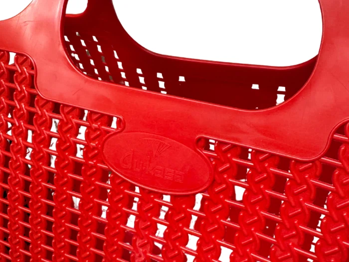 Nærbillede af en knaldrød plastkurv med vævet design og solid hank, der viser et logo præget på forsiden.