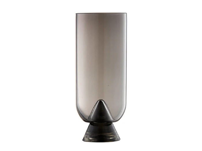 Et højt, cylindrisk, røggråt glas med en afrundet bund og en kegleformet støtte i bunden på en hvid baggrund.