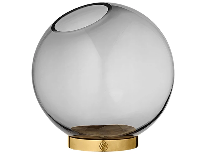 En rund, klar glasvase med en skrå åbning, sat på en skinnende, cirkulær guldbase.