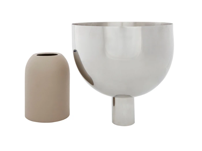 En matbeige keramikvase står ved siden af en større, reflekterende sølvmetallisk skål med cylindrisk bund mod en hvid baggrund.