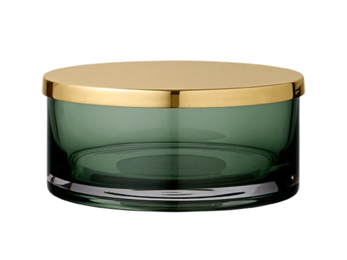 En rund, mørkegrøn glasbeholder med et skinnende guldmetallåg, vist på en hvid baggrund.
