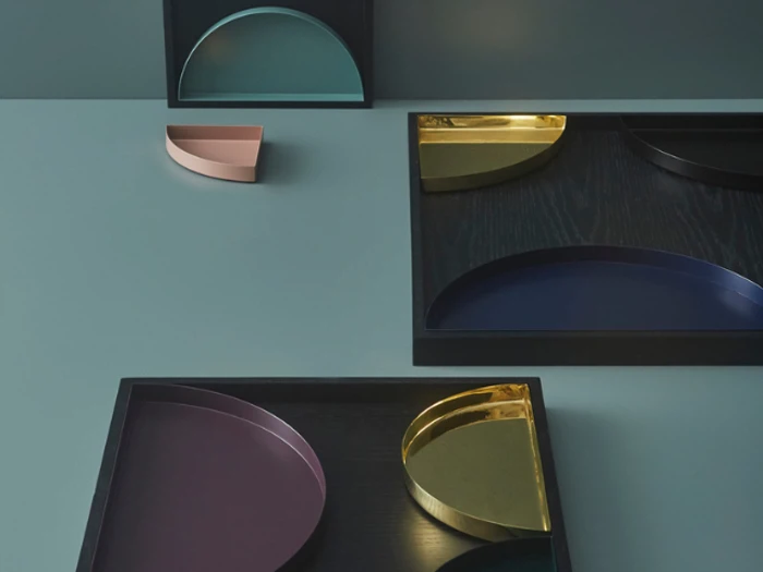 Geometriske bakker i forskellige farver - pink, guld, marineblå, blågrøn og lilla - er arrangeret på en blågrå overflade, nogle inden i sorte rektangulære rammer.