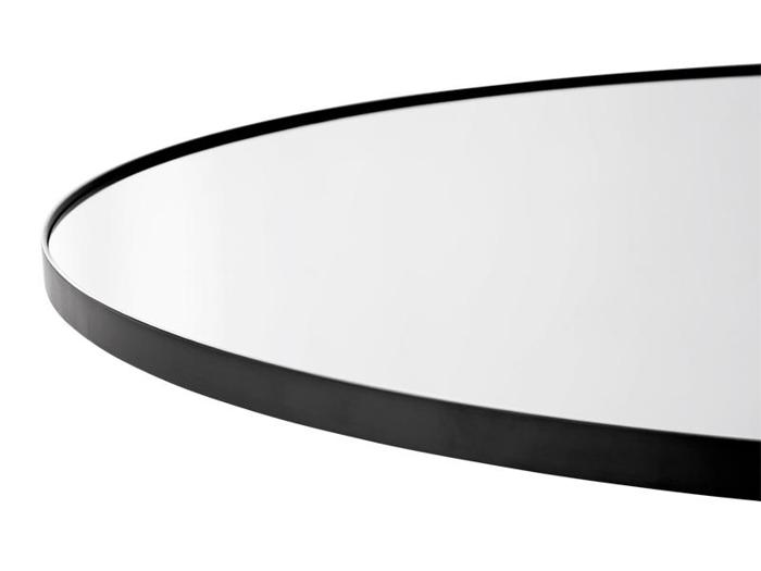 Nærbillede af et rundt spejl med en tynd, sort metalramme mod en hvid baggrund.