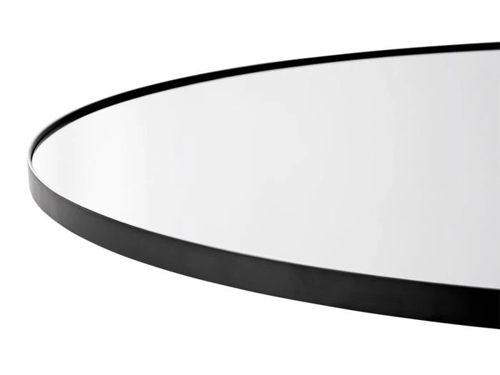 Nærbillede af et rundt spejl med en tynd, sort metalramme mod en hvid baggrund.