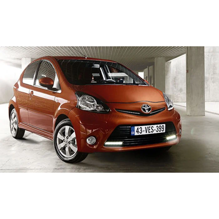 En rød Toyota Aygo hatchback parkeret i en moderne, veloplyst garage med en europæisk nummerplade, set fra en vinkel forfra til venstre.